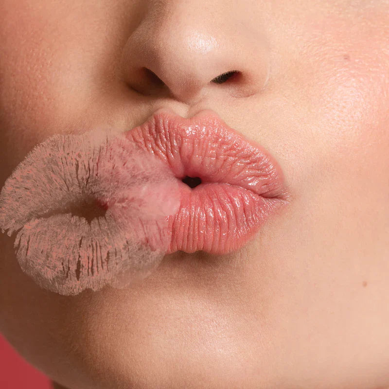 A woman wearing tinted lip balm kisses a sheet of glass