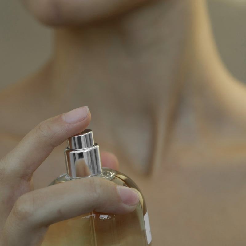 A person is spraying perfume on their neck
