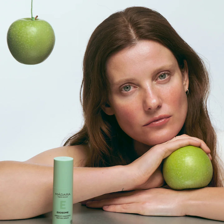 Exosome Longevity Radiance Peptide Serum von Mádara - Produktfoto mit Model und grünen Äpfel