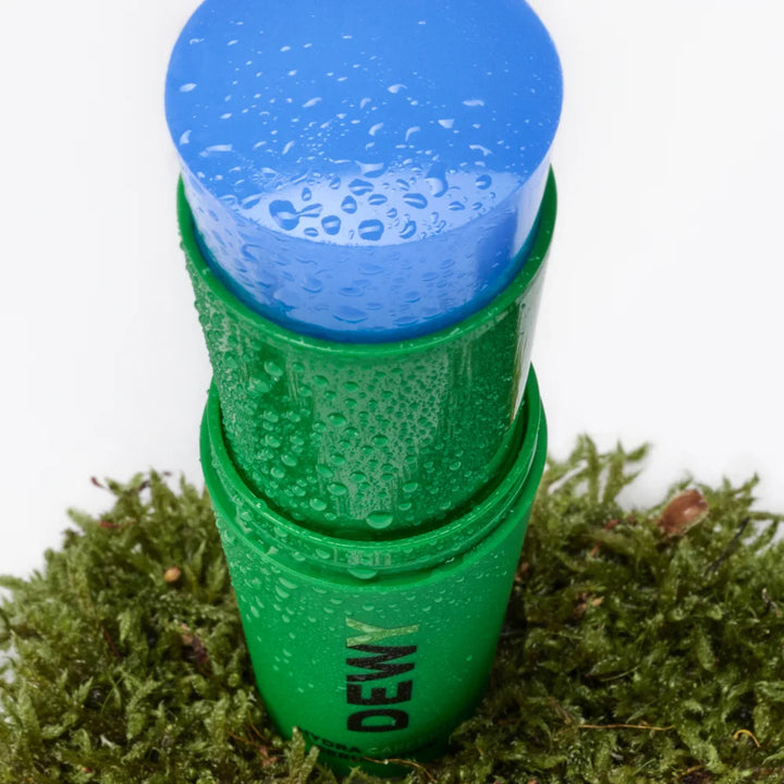 Dewy Hydra Caffeine Serum Stick von Mádara - geöffnet, steht auf feuchtem Moos