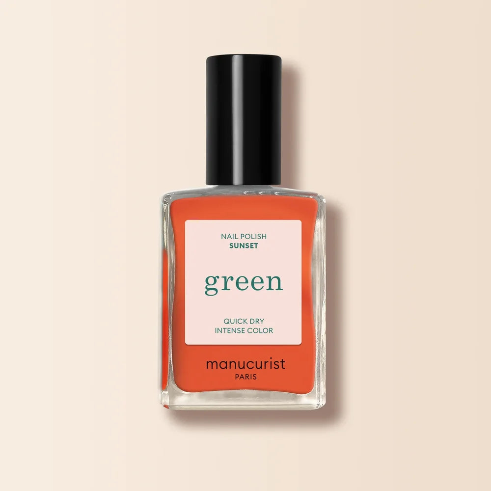 Manucurist Paris Green Nagellack in Sunset - leuchtend korall-oranger Farbton in Glasflasche mit schwarzem Verschluss auf neutralem beigem Hintergrund