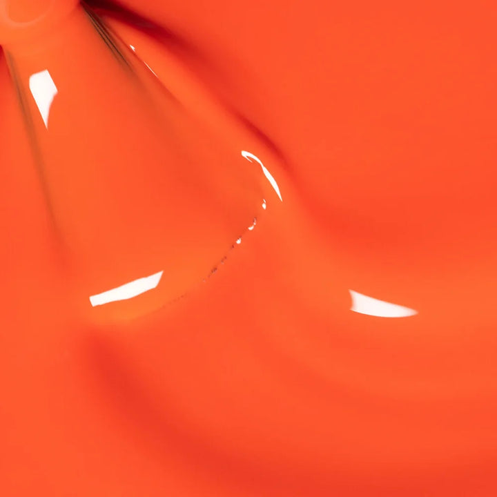 Nahaufnahme des Manucurist Sunset Nagellackpinsels, der die leuchtende korall-orange Formel und glatte Auftragstextur vor passendem orangem Hintergrund zeigt