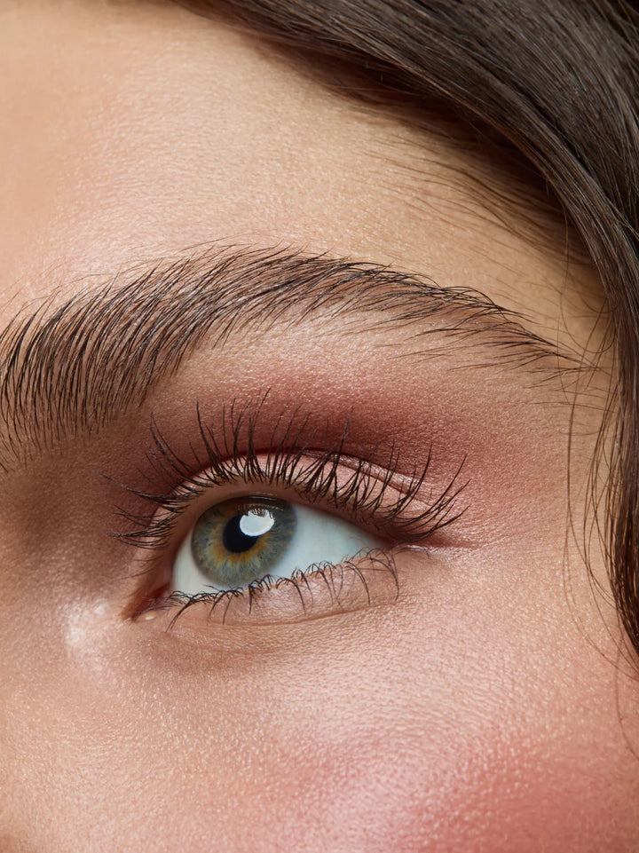 Nahaufnahme eines Auges mit brauner Mascara und schimmerndem Augen-Make-up