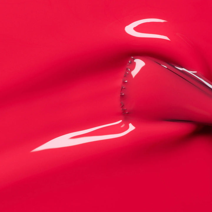 Nahaufnahme des Manucurist Bougainvillea Nagellackpinsels, der die leuchtende korallrote Formel und glatte Auftragstextur zeigt