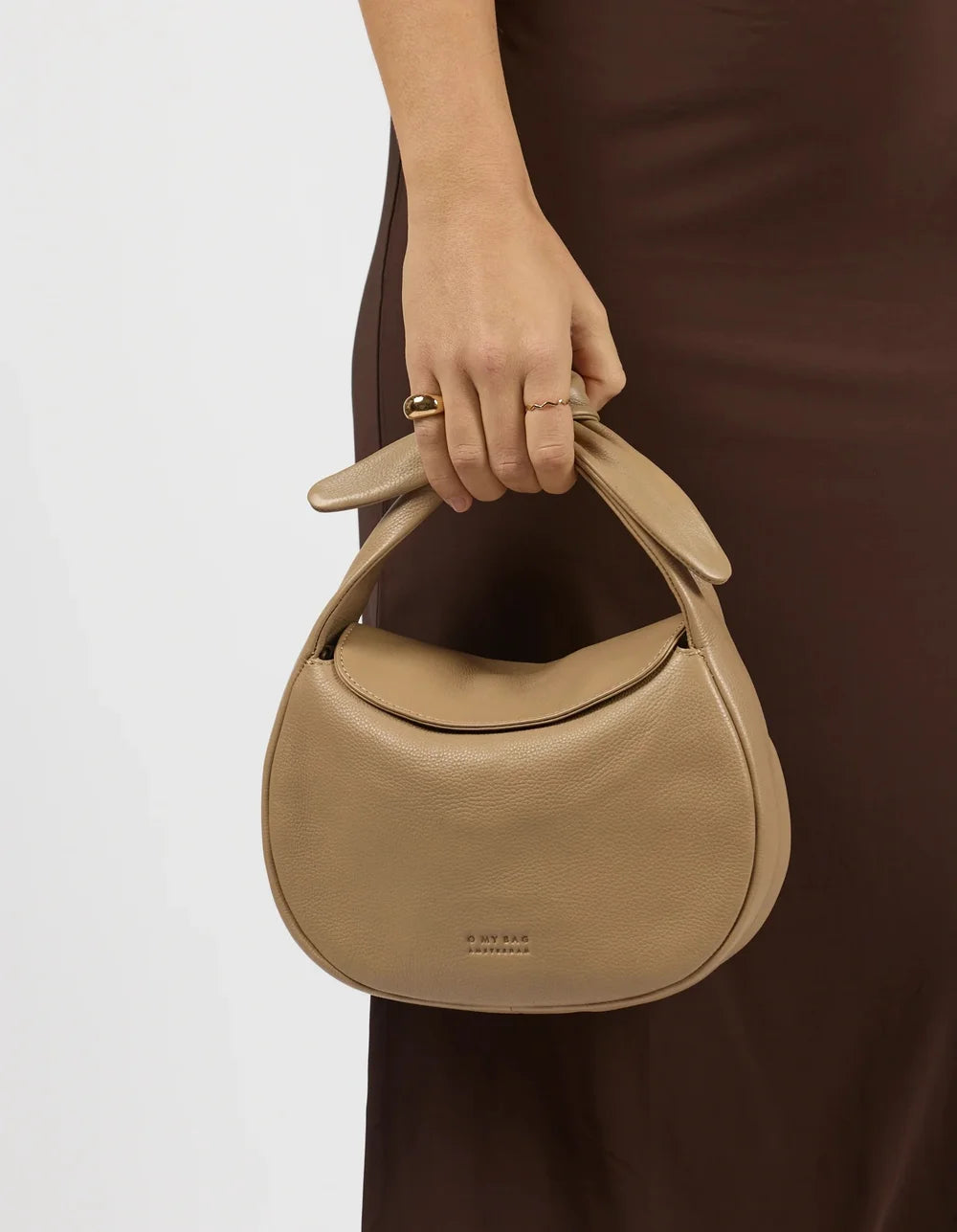 O My Bag Coco Croissant Dark Sand – kleine Handtasche mit Knotenhenkel mit der Hand getragen