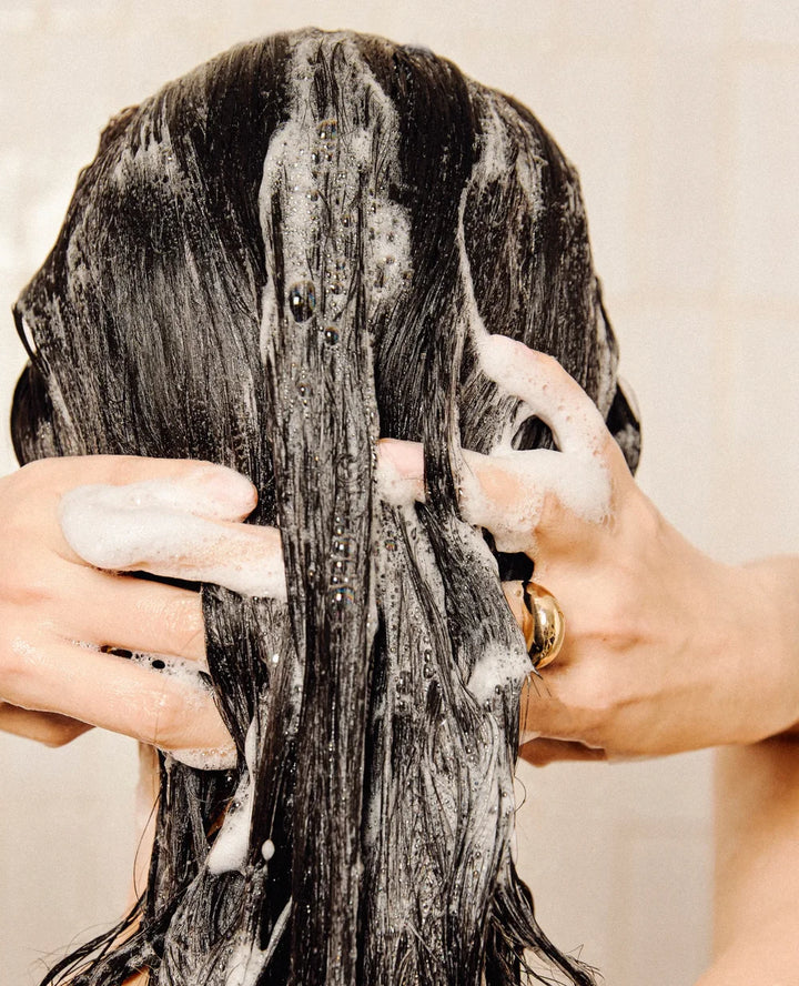 Frau wäscht ihr Haar mit Rahua Haarpflege unter der Dusche