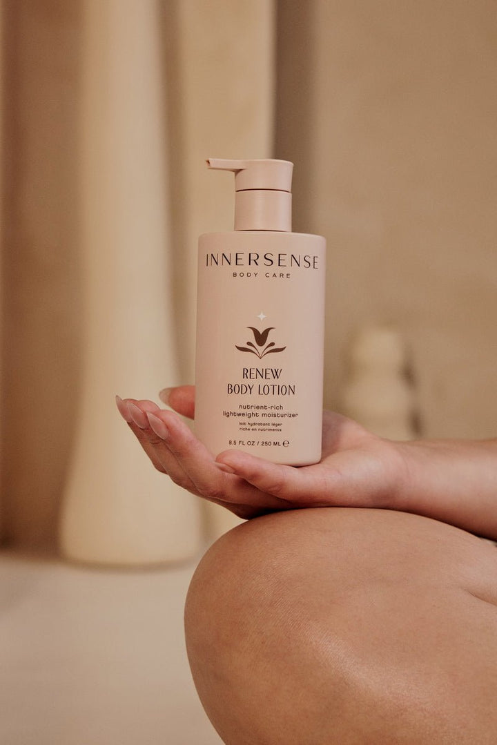 Innersense Renew Body Lotion in der Hand vor warm-beigem Hintergrund