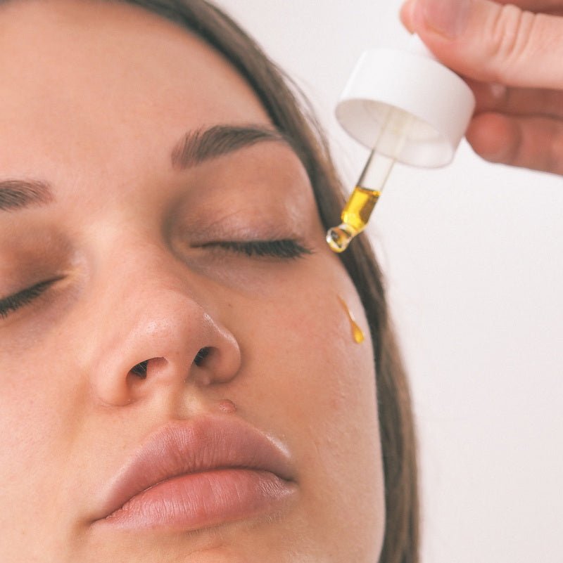Model trägt Wildcrafted Organics Bakuchiol Serum mit Pipette auf die Wangenpartie auf