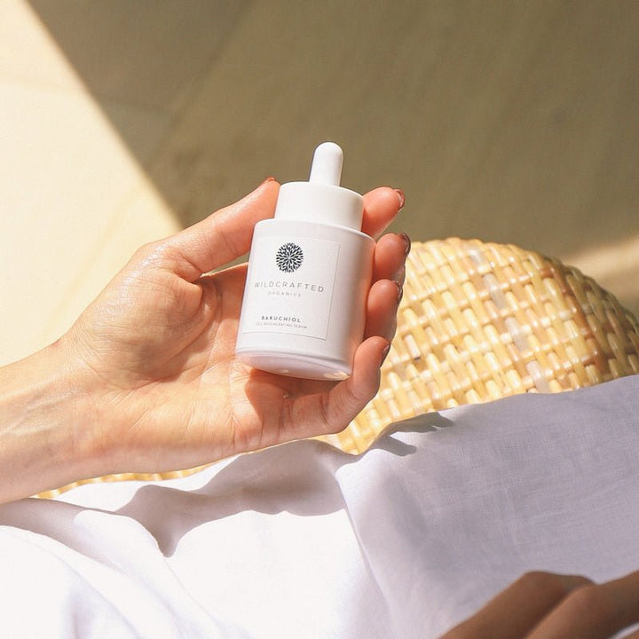 Hand hält Wildcrafted Organics Bakuchiol Cell-Regenerating Serum Flasche im Sonnenlicht