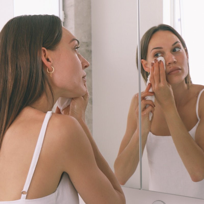 Model reinigt Gesicht mit Wildcrafted Organics Luxury Cleansing Cloth vor dem Spiegel