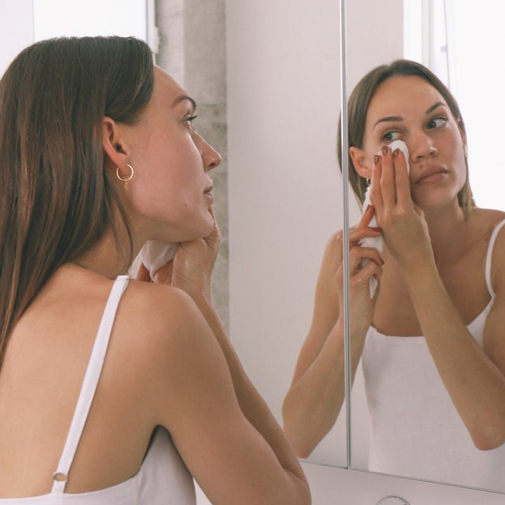 Model reinigt Gesicht mit Wildcrafted Organics Luxury Cleansing Cloth vor dem Spiegel