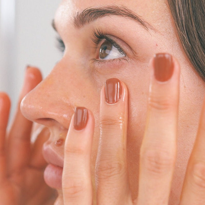 Model trägt Wildcrafted Organics Wildflowers Rejuvenating Serum auf die Wangenpartie auf und zeigt strahlende, gepflegte Haut